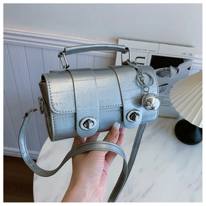 Detail of silver metallic barrel bag with vintage twist locks and a polished ball charm
