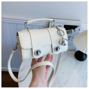 Detail of cream white faux leather handbag with silver twist locks and metallic ball charm