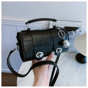 Detail of black crocodile texture cylinder bag with silver twist locks and metal ball charm
