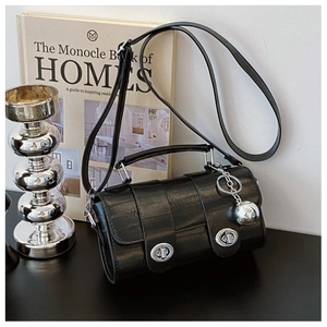 Detail of black faux crocodile cylinder handbag with silver twist locks and sphere charm