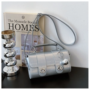 Detail of silver crocodile pattern handbag featuring metal twist locks and a sphere charm