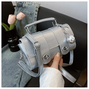 Detail of silver crocodile pattern bag with dual knob locks and metal ball charm