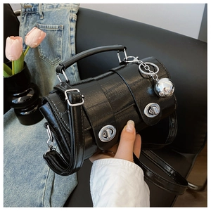 Detail of black crocodile texture bag with silver twist locks and spherical charm