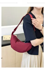 Vista indossata di una borsa a tracolla a mezzaluna bordeaux con cinturino largo