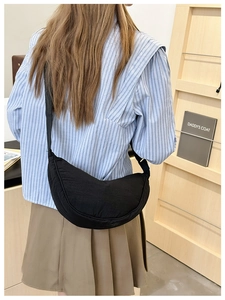 Borsa a tracolla nera a mezzaluna abbinata a una camicia a righe per look casual