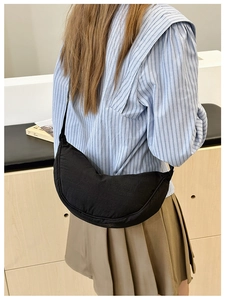 Borsa a tracolla a mezzaluna minimalista in tela nera indossata da una modella nel tempo libero