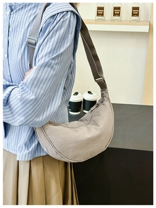 Primo piano di una borsa a tracolla a mezzaluna in nylon taupe indossata da un modello