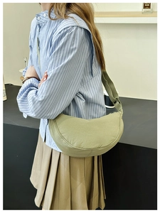 Dettaglio della borsa a mezzaluna in tela verde oliva indossata da una modella in stile casual
