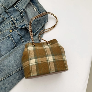 Detailed top view of a plaid wool bucket bag with gold chain strap on denim jacket
