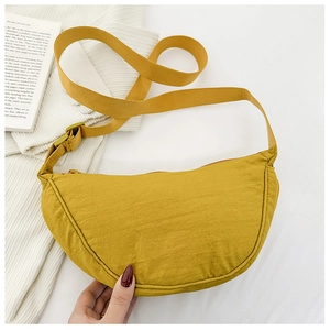 Dettaglio di una borsa a tracolla gialla in nylon a mezzaluna su sfondo in maglia