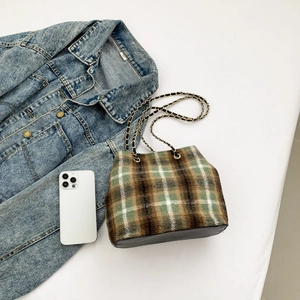 Detail of vintage plaid bucket bag with gold chain strap and leather patchwork base