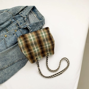 Detailed view of the plaid pattern and woven chain strap on the bucket bag