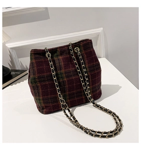 Detail of vintage plaid bucket bag featuring textured wool and woven gold chain strap