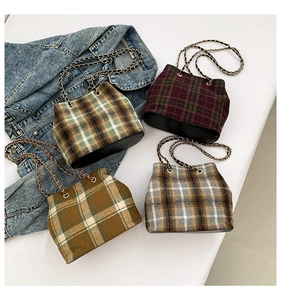 Flat lay of plaid tweed bucket bags with chain straps on denim jacket detail