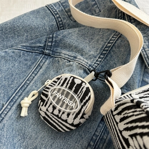 Borsa rotonda in tela a righe bianche e nere con logo FANYISSA su fondo denim