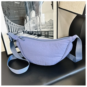 Dettaglio di una borsa a mezzaluna in nylon blu-grigio con tracolla regolabile e zip