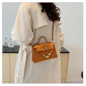 Detail view of the brown crocodile texture and metal clasp on a stylish shoulder bag