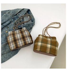 Flat lay of retro plaid bucket bags with leather trim and gold chain straps on denim