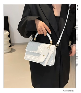 Close-up of white embossed leather handbag with woven handle and gold metal hardware