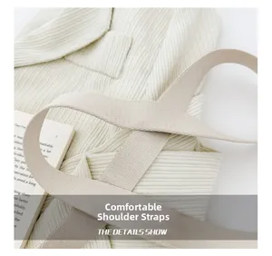 Dettaglio della tracolla larga in tessuto su borsa in tela crema con accessorio libro