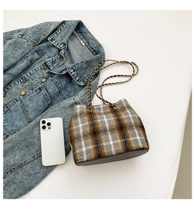 Close-up of vintage plaid tweed bucket bag with leather base and woven chain strap