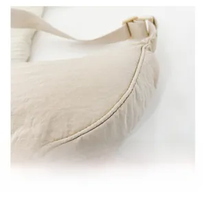 Dettaglio macro di cuciture fini e fibbia in metallo su borsa a tracolla in nylon beige
