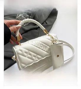 Detail of white quilted crossbody bag with woven handle and small attached coin purse