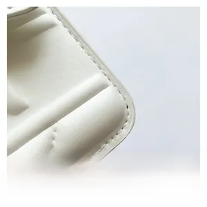 Detailed macro view of white quilted faux leather material with precise stitching on handbag