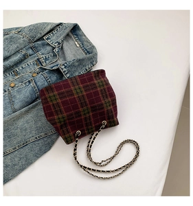 Detailed view of burgundy plaid fabric texture and woven metal chain on crossbody bag