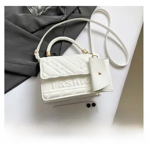 Close-up of white quilted handbag with woven handle and phone for size reference