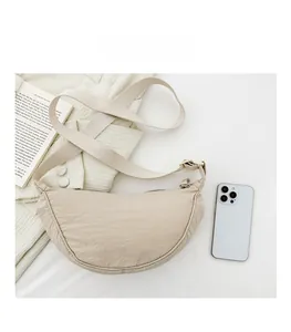 Dettaglio della borsa a mezzaluna beige in nylon con smartphone per confronto dimensioni