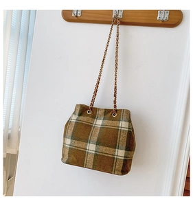 Detail of a brown and beige plaid bucket bag with a golden metal chain hanging on a hook