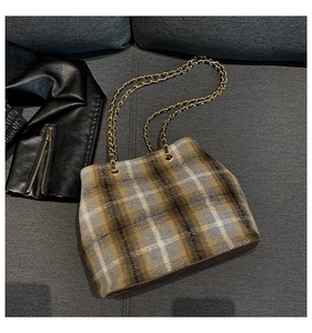 Close-up of vintage brown plaid wool bucket bag featuring golden chain shoulder straps