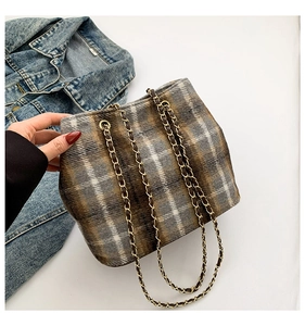 Detail of grey plaid wool bucket bag featuring a premium metal chain shoulder strap