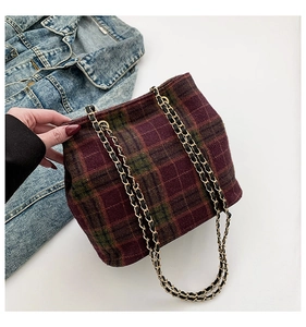 Detail of red and green plaid fabric tote with gold woven chain shoulder straps