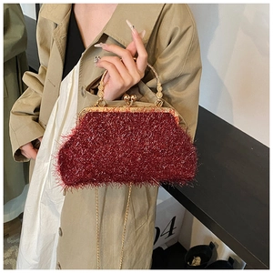 Détail d'une pochette vintage bordeaux avec poignée anneau dorée et fermoir métallique