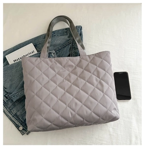 Λεπτομέρεια flat lay γκρι καπιτονέ τσάντας tote με ευρύχωρο σχέδιο διαμαντιών και λαβές