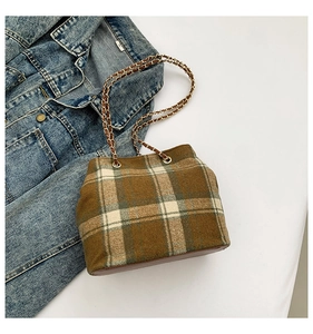 Detail of classic plaid bucket bag featuring a brown chain strap and vintage fabric texture