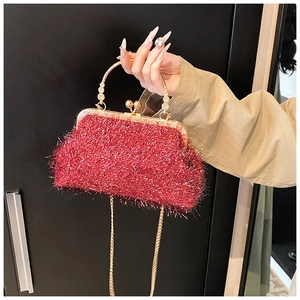 Détail d'un sac de soirée rouge à paillettes avec anse dorée et fermoir à boule