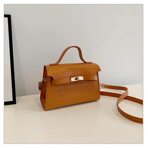 Brown crocodile pattern leather satchel with top handle and gold twist lock in white studio