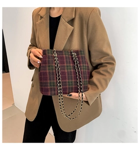 Detail of colorful plaid shoulder bag with golden chain strap on a khaki blazer