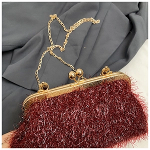 Close-up of dark red fringe fabric detail with golden metal frame and chain strap
