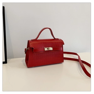 Detail of red crocodile texture handbag with golden buckle and top handle