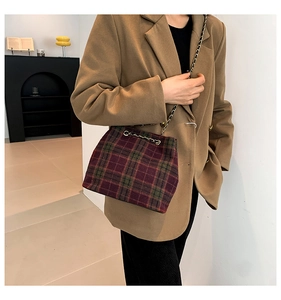 Detail of wool plaid shoulder bag featuring burgundy check pattern and metal chain strap