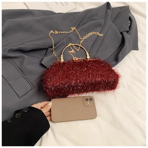 Burgundy plush evening clutch bag featuring golden metal handle and chain strap detail