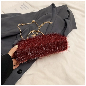 Macro view of burgundy plush dinner bag with gold handles and textured tassel fringe