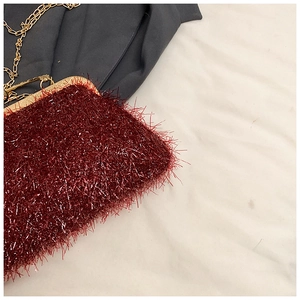 Detail of wine red plush evening bag with metallic glitter texture and gold chain strap