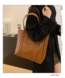 Detail of a brown PU leather tote bag with vertical stitching and handy front pocket