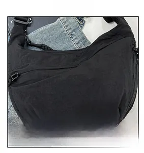 Detailed close-up of a black crescent nylon crossbody bag with minimalist zipper and strap