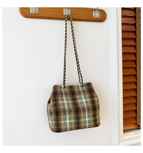 Detail of tweed bucket bag with brown plaid pattern and gold chain leather strap